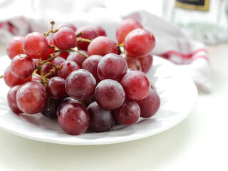 Fresh red grapes fruit in white plate on white background