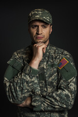American soldier in camouflage uniform and cap suffering from ptsd isolated on black.