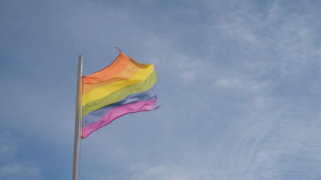 Gay pride rainbow flag waving on blue sky background. Symbol of the LGBT community on a pride. Human Rights, Equal rights, Peace and freedom. Support LGBTQ community