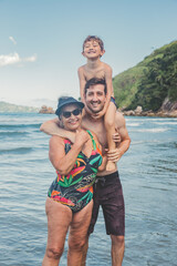 Avó, filho e neto sorrindo na praia no verão