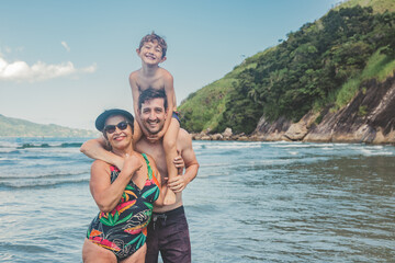 Avó, filho e neto sorrindo na praia no verão