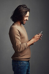 Now thats a meme worth sharing. Studio shot of a handsome young man using a mobile phone against a gray background.