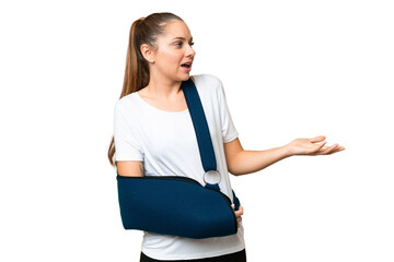 Young blonde woman with broken arm and wearing a sling over isolated chroma key background with...