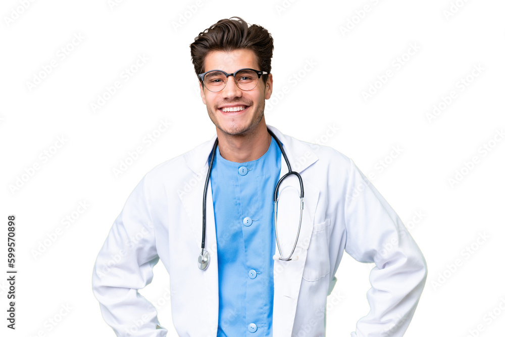 Wall mural Young doctor man over isolated background posing with arms at hip and smiling