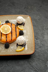 front view yummy cake dessert with lemon slices and coconut candies on dark desk pie dessert tea...