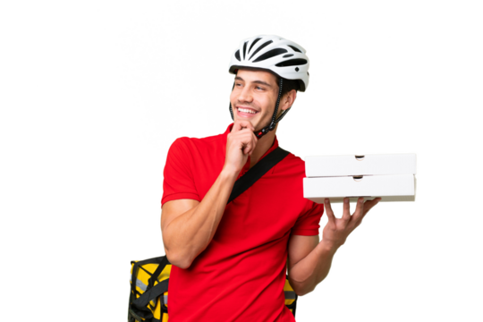 Pizza delivery man with work uniform picking up pizza boxes over isolated background looking up while smiling