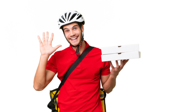 Pizza delivery man with work uniform picking up pizza boxes over isolated background saluting with hand with happy expression