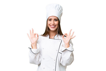 Young chef caucasian woman over isolated background showing an ok sign with fingers