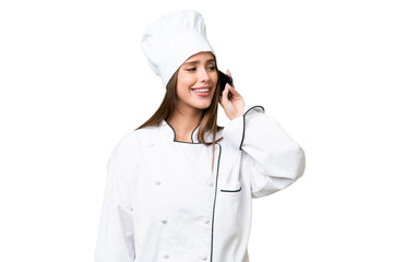 Young chef caucasian woman over isolated background keeping a conversation with the mobile phone