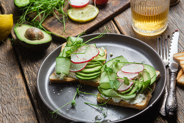 White bread toasts with cream cheese, avocado, cucumber and radish in a plate