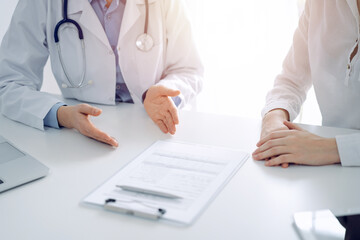 Stethoscope lying on the tablet computer in front of a doctor and patient sitting opposite each other at the background . Medicine, healthcare concept