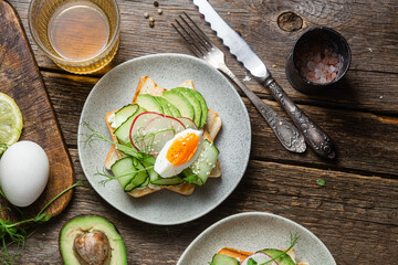 White bread toasts with cream cheese, egg, avocado, cucumber and radish in a plate