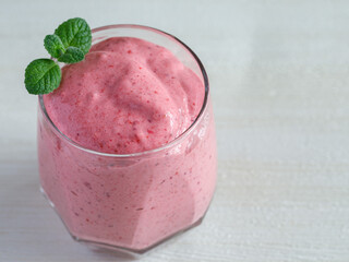 Healthy Strawberry or Raspberry Cream mousse in glass on a white wooden table with mint leaves. Delisious summer dessert. Top view, close up