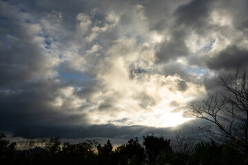 silhouette of the sun on a dark rainy sky; a sunshine after the rain