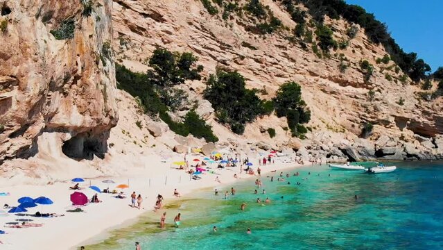 Cala Mariolu Beach Sardinia Italy, a beautiful beach full of beach people sunbathing and swimming in turquoise water. Cala Gonone Baunei, Sardinia, Italy Golfo Di Orosei