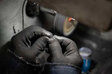 Lapidary worker polishing boulder precious stone or metal. no face, unrecognizable person.