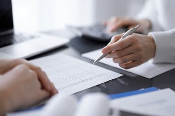 Woman accountant using a calculator and laptop computer while counting taxes for a client. Business audit and finance concepts