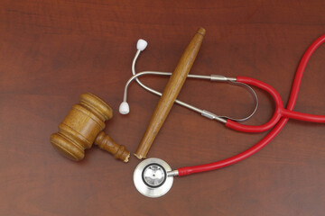 Red stethoscope and broken judge gavel on table. Doctor mistake and court concept.