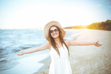 Fototapeta na wymiar Portrait of a happy smiling woman in free happiness bliss on ocean beach enjoying nature during travel holidays vacation outdoors. View through white blurred flowers
