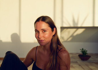 retrato de cabeza  bella joven mujer caucasica sentada en un estudio de yoga con luz del atardecer