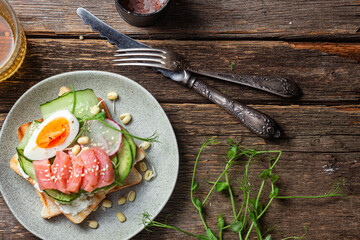 toasts with cream cheese, salmon, egg, avocado, cucumber  in a plate