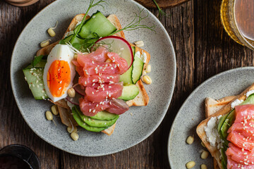toasts with cream cheese, salmon, egg, avocado, cucumber  in a plate