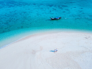 men and women walking on a sandbar in the ocean of Koh lipe Southern Thailand during vacation