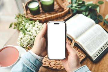 Phone in hands with an isolated screen and an open bible, space for your text