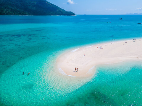 men and women walking on a sandbar in the ocean of Koh lipe Southern Thailand during vacation