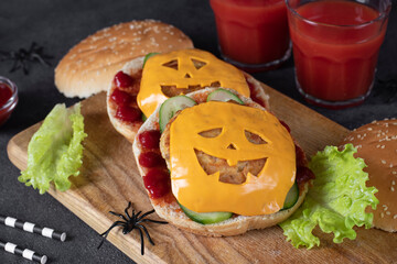 Two funny monster chicken burgers with toast cheese, ketchup and cucumber on wooden board. Creative...