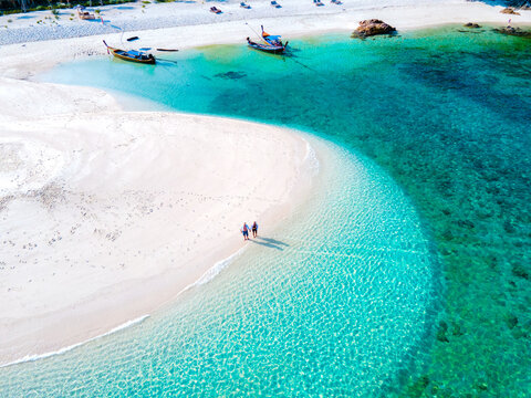 men and women walking on a sandbar in the ocean of Koh lipe Southern Thailand during vacation