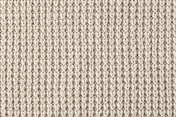 Fragment of beige knitted clothes of rough knitting