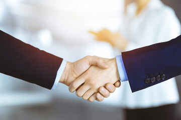 Business people use a tablet computer for discussion of their new project, standing in a sunny modern office. Unknown businessman or male entrepreneur with a colleague at workplace