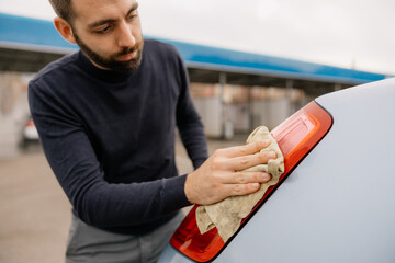 A man cleaning car with microfiber cloth, car detailing.