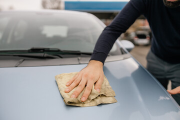 A man cleaning car with microfiber cloth, car detailing.