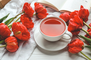 Beautiful spring composition, good morning concept. Cup of tea, peonies, open book
