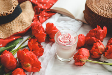 Candle, tulips and open book in home interior.
