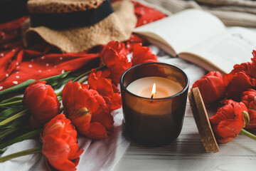 Cozy spring composition, burning candle, peonies and hat