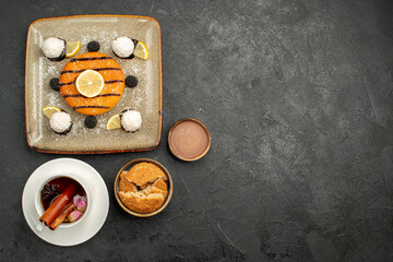 top view delicious little pie with coconut candies and cup of tea on dark background candy biscuit cake pie cookie sweet