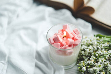 Burning candle with flower and hearts on white background with space for text