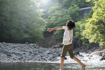 逆光の中 夏の川で遊ぶ小学生や子供の旅行のイメージ...