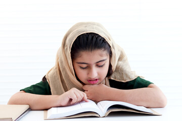 Concentrate Muslim student girl with beautiful eyes wears traditional hijab costume, study and do...