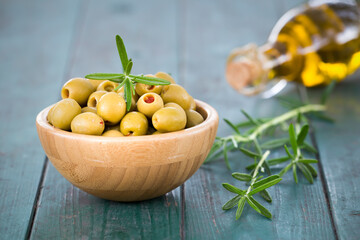 Fresh healthy green olives with rosemary and virgin oil in a bottle. Summer food background.