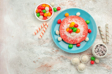 top view delicious pink cake with colorful candies on white background candy dessert color rainbow goodie cake
