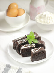Brownies Kukus or Chocolate Steam Cake Brownies with marble chocolate glaze on top. Served in white ceramics pllate. Selective focus, white background