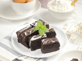 Brownies Kukus or Chocolate Steam Cake Brownies with marble chocolate glaze on top. Served in white ceramics pllate. Selective focus, white background