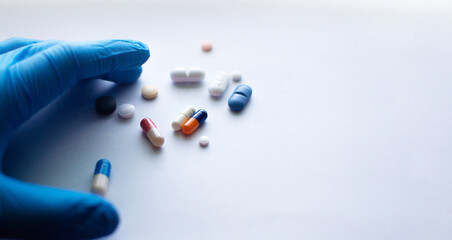 colored medicines on white paper with a blue gloved hand to the side