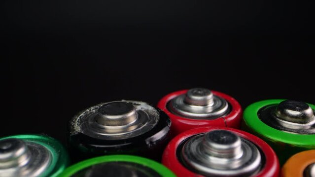 Camera zooms in on used alkaline batteries, commonly used in electronic devices. Filmed in macro on a dark surface.