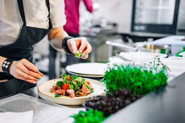chef hand cooking Roast beef salad with vegetables on restaurant kitchen