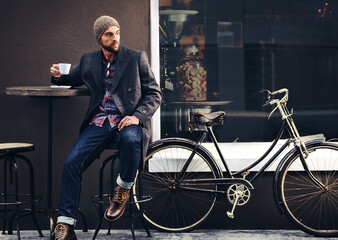 Thinking, cafe and man with a coffee, bicycle and relax with thoughts, wonder and eco friendly transport. Male person, biker and guy with tea, outdoor and travel with winter fashion and a cappuccino